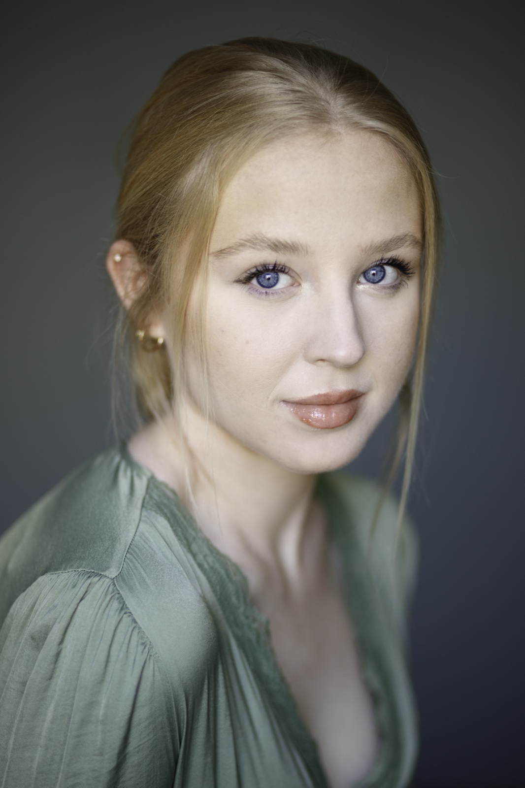 Close-up portrait of a woman with blue eyes in a green top