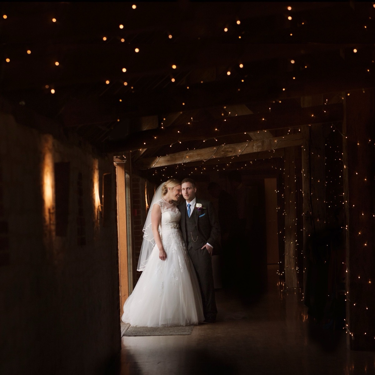Bride and groom beneath warm lights at Bury Court Barn