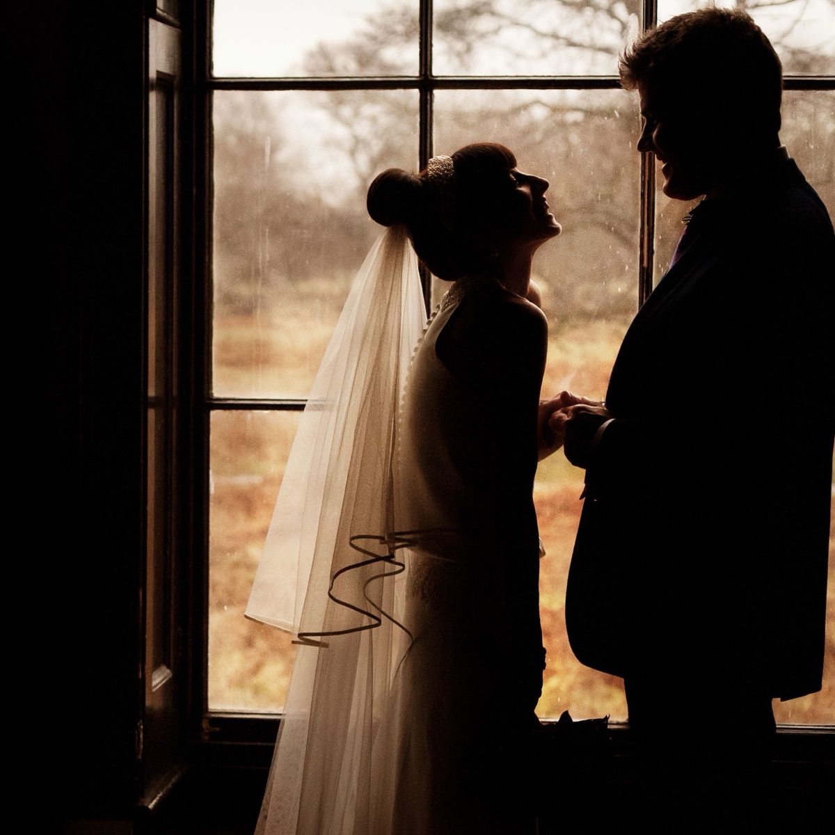 Bride and groom silhouetted by a window near Hampton Court